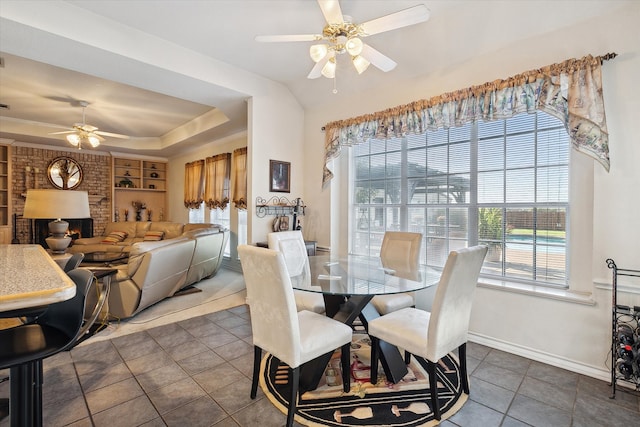 dining area featuring dark tile patterned floors, ceiling fan, a fireplace, and built in features