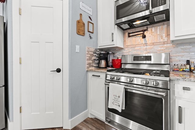 kitchen with tasteful backsplash, light stone countertops, stainless steel appliances, and white cabinets