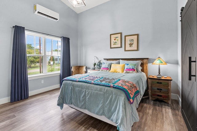 bedroom featuring vaulted ceiling, hardwood / wood-style flooring, a barn door, and a wall unit AC