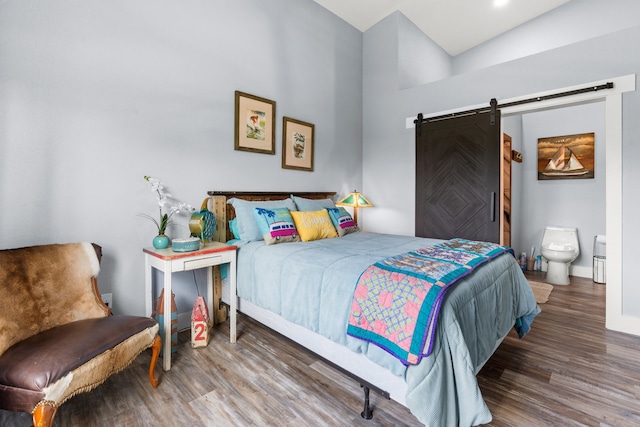 bedroom with vaulted ceiling, ensuite bathroom, hardwood / wood-style floors, and a barn door