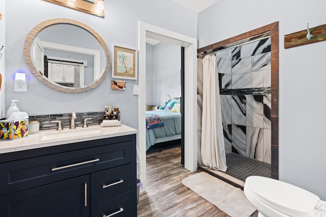 bathroom with a shower with shower curtain, hardwood / wood-style floors, vanity, and toilet