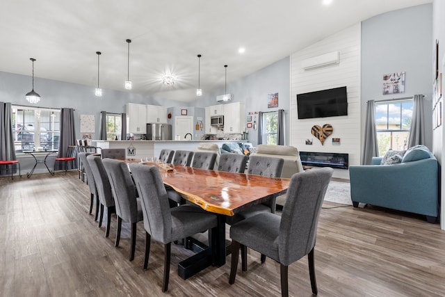 dining area featuring high vaulted ceiling, a large fireplace, hardwood / wood-style floors, and a wall mounted air conditioner