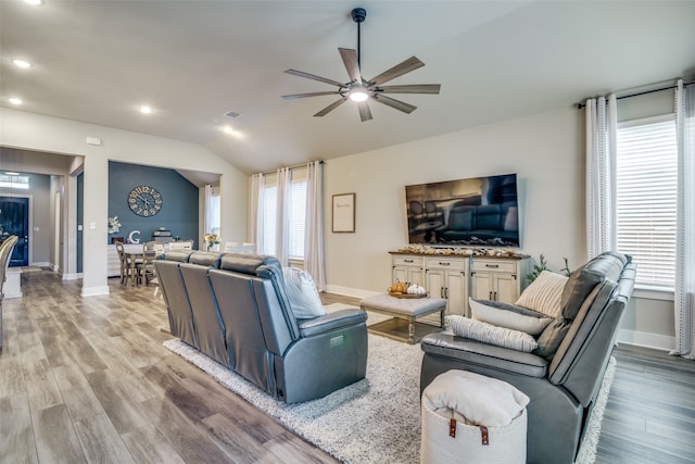 living room featuring ceiling fan, light hardwood / wood-style flooring, and vaulted ceiling