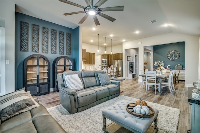 living room featuring light hardwood / wood-style floors, ceiling fan, and vaulted ceiling