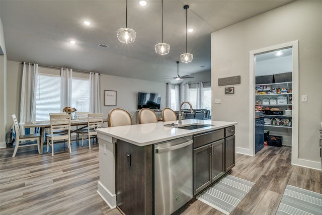 kitchen featuring pendant lighting, dishwasher, sink, a kitchen island with sink, and dark brown cabinets