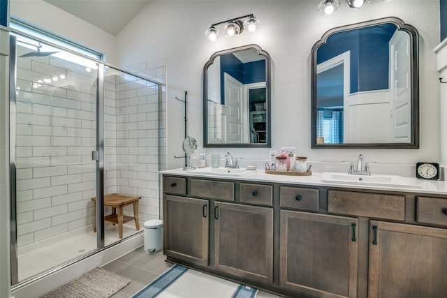 bathroom featuring walk in shower, vanity, vaulted ceiling, and tile patterned floors