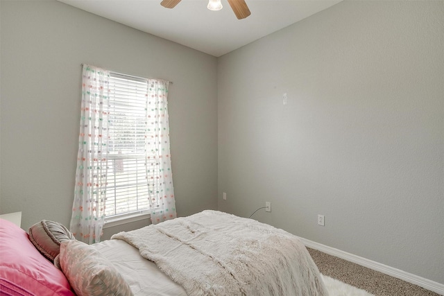 bedroom with a ceiling fan, baseboards, multiple windows, and carpet
