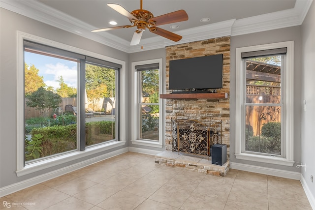 unfurnished living room featuring ceiling fan, a fireplace, light tile patterned floors, and crown molding