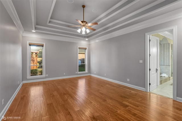 unfurnished room with a tray ceiling, ceiling fan, plenty of natural light, and hardwood / wood-style floors