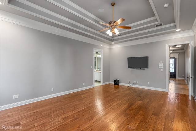 unfurnished room with a raised ceiling, ceiling fan, hardwood / wood-style floors, and crown molding