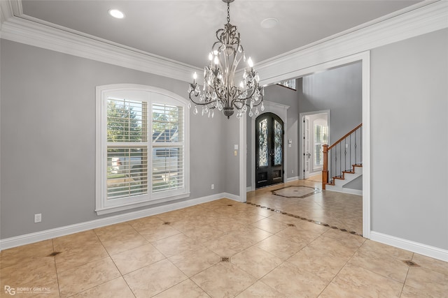 tiled entrance foyer with ornamental molding, french doors, and an inviting chandelier