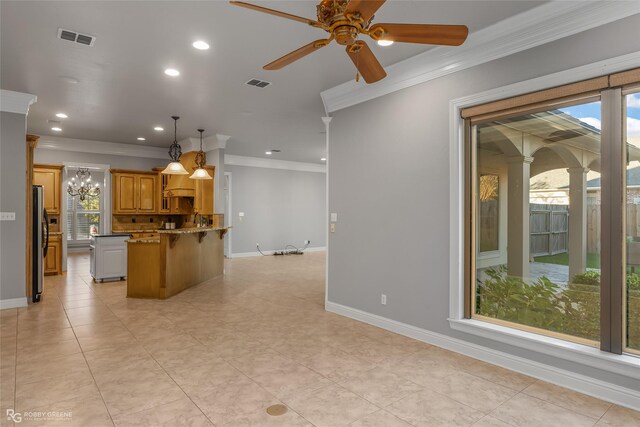 kitchen with ornamental molding, hanging light fixtures, stainless steel refrigerator, and a breakfast bar area