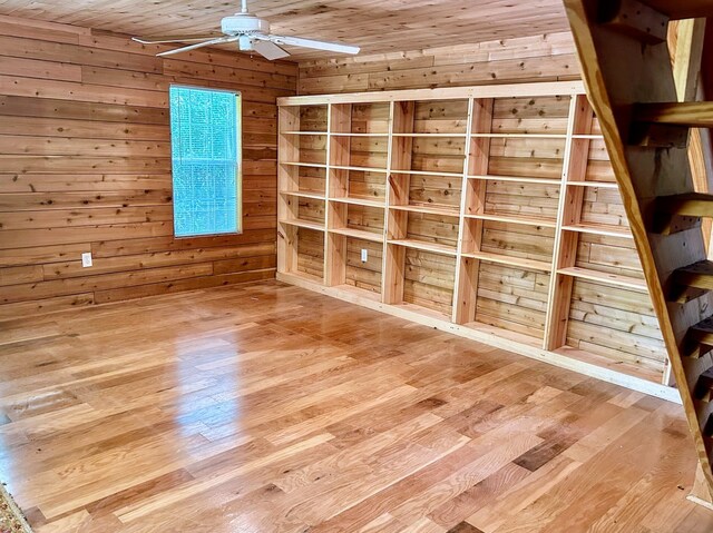 interior space with ceiling fan, wooden walls, wood ceiling, and hardwood / wood-style floors