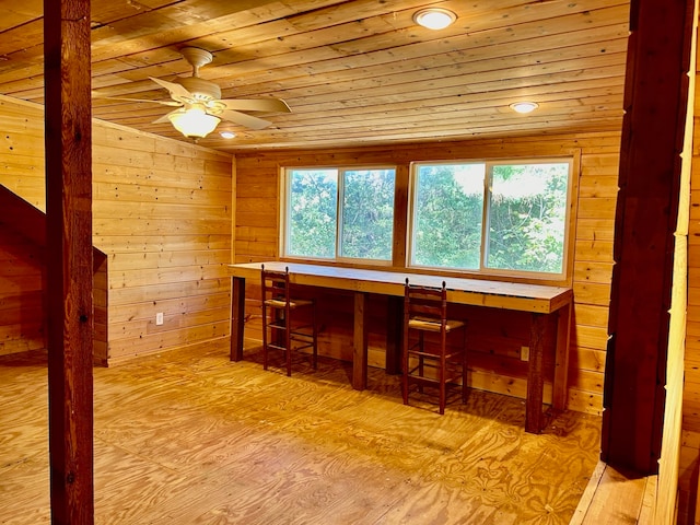 interior space with wood walls, built in desk, light hardwood / wood-style floors, and wooden ceiling