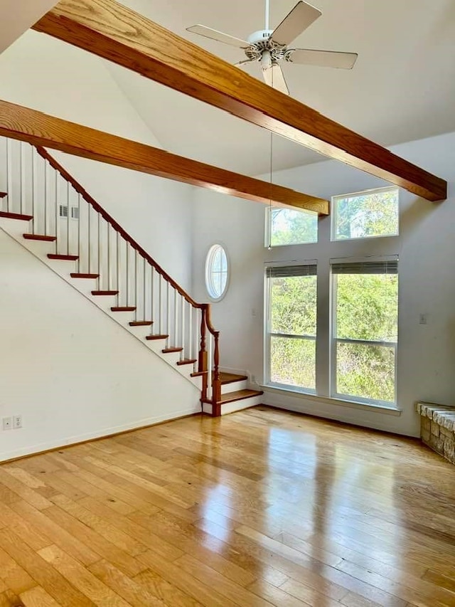 unfurnished living room featuring light wood-type flooring, beam ceiling, and high vaulted ceiling