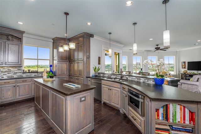 kitchen featuring appliances with stainless steel finishes, a kitchen island, ceiling fan, and plenty of natural light