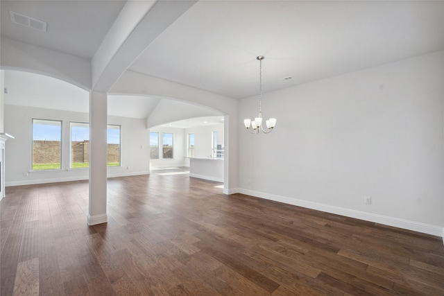 spare room with an inviting chandelier and dark hardwood / wood-style floors