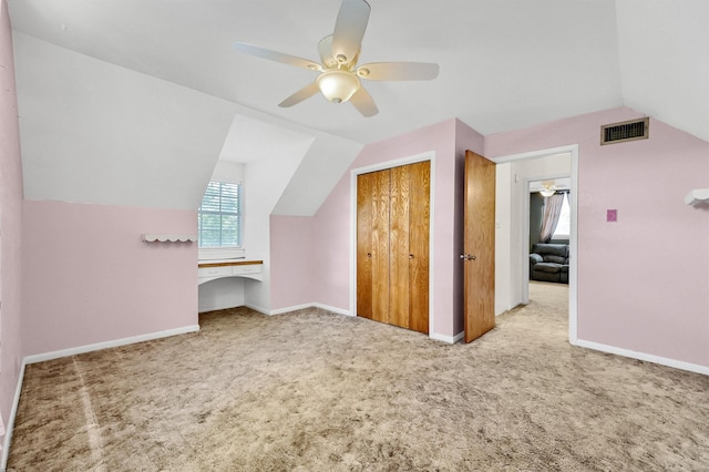 bonus room featuring light carpet, built in desk, vaulted ceiling, and ceiling fan