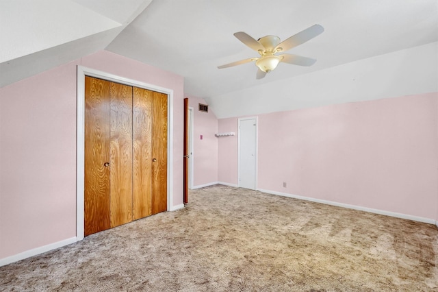 unfurnished bedroom featuring ceiling fan, a closet, vaulted ceiling, and carpet