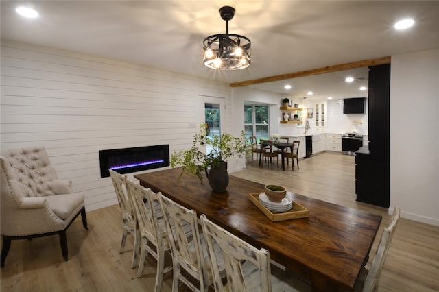 dining area with light hardwood / wood-style flooring, a notable chandelier, and sink