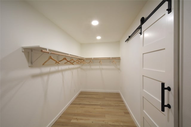 spacious closet with light hardwood / wood-style floors and a barn door