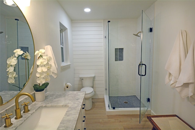 bathroom featuring wood-type flooring, vanity, toilet, and an enclosed shower