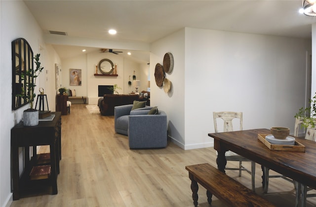 living room with ceiling fan, light hardwood / wood-style flooring, lofted ceiling, and a large fireplace