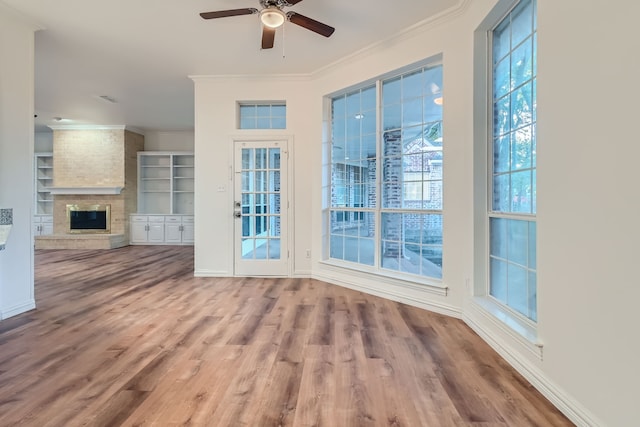 unfurnished living room featuring ceiling fan, ornamental molding, wood-type flooring, and a large fireplace