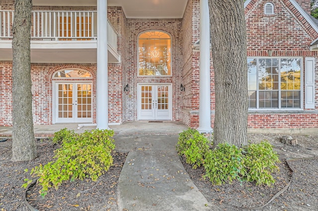 view of exterior entry with a balcony and french doors