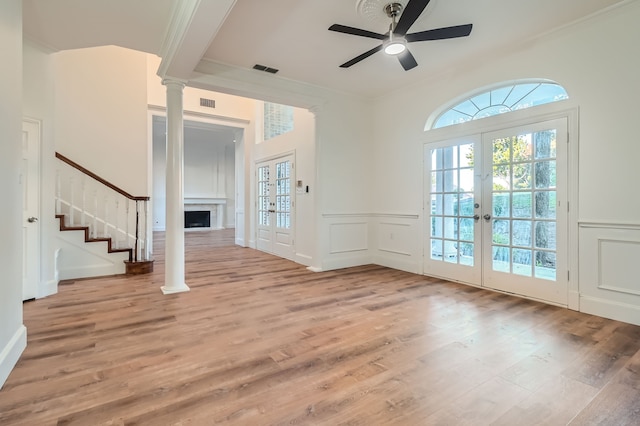 unfurnished living room featuring french doors, light wood-type flooring, ornamental molding, and ceiling fan