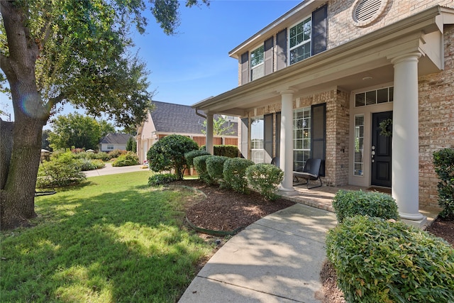 doorway to property featuring a lawn and covered porch