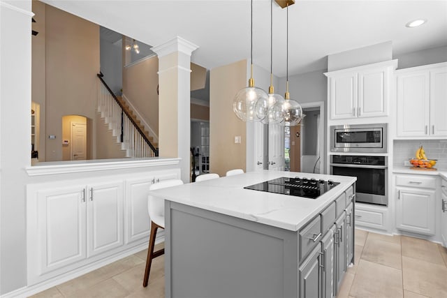 kitchen featuring a breakfast bar area, stainless steel appliances, a center island, light stone countertops, and white cabinets