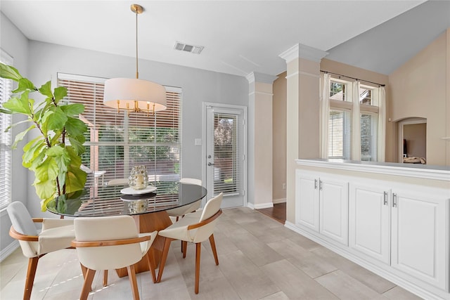 dining space featuring ornate columns, a chandelier, and a wealth of natural light