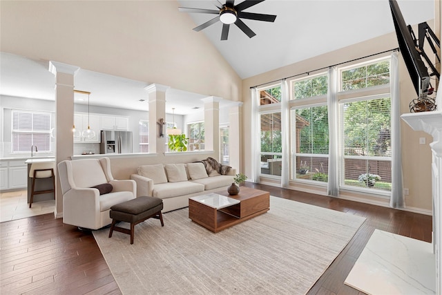 living room with a high end fireplace, ceiling fan, dark wood-type flooring, high vaulted ceiling, and decorative columns