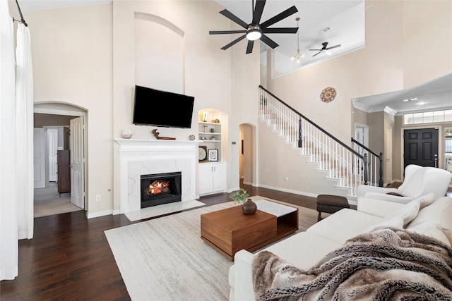 living room featuring a high ceiling, built in features, and a high end fireplace