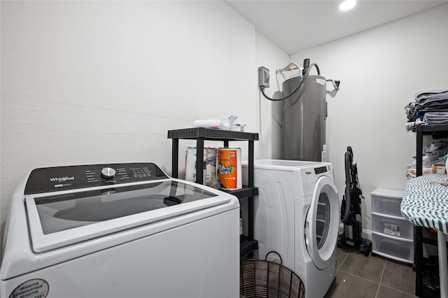 laundry area featuring water heater, dark tile patterned flooring, and washer and dryer