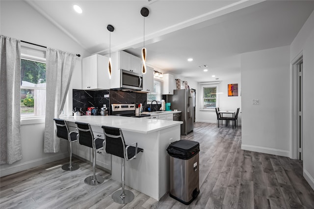 kitchen featuring kitchen peninsula, white cabinetry, pendant lighting, and range with electric cooktop