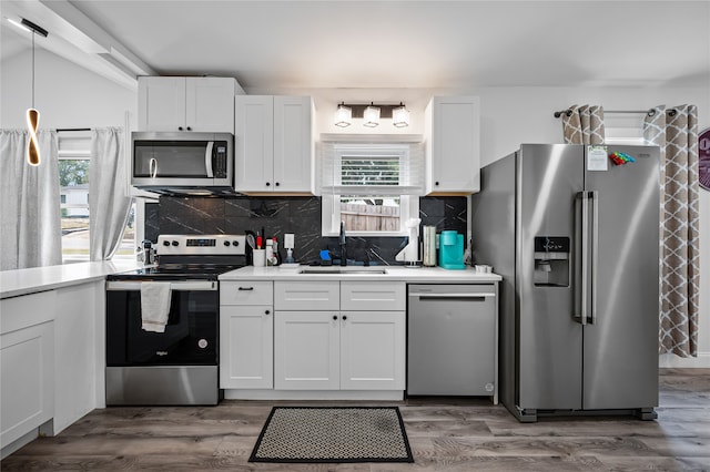 kitchen featuring stainless steel appliances, white cabinetry, hanging light fixtures, and dark hardwood / wood-style flooring