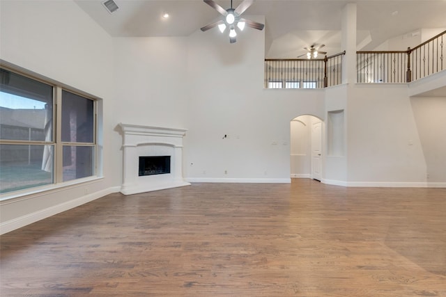 unfurnished living room featuring ceiling fan, hardwood / wood-style floors, and a high ceiling