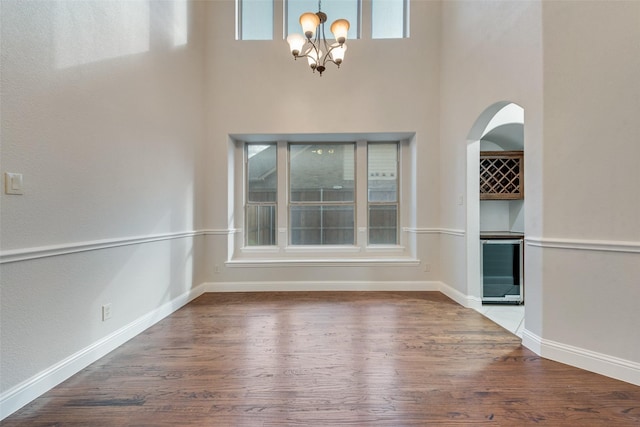 unfurnished dining area with hardwood / wood-style floors, wine cooler, plenty of natural light, and a notable chandelier