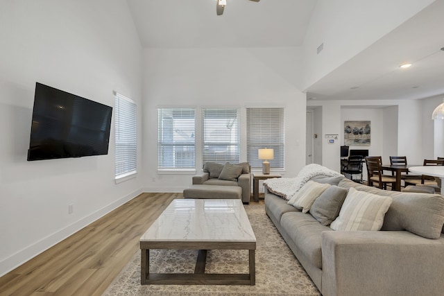 living room featuring light wood-type flooring, ceiling fan, and high vaulted ceiling