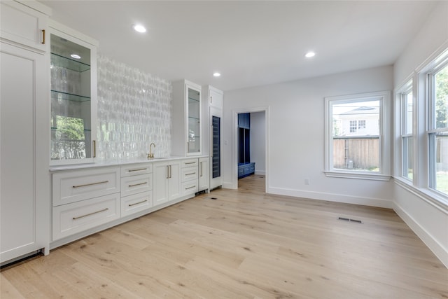 interior space with white cabinets, sink, and light wood-type flooring