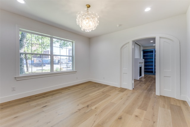 spare room with a chandelier and light hardwood / wood-style flooring