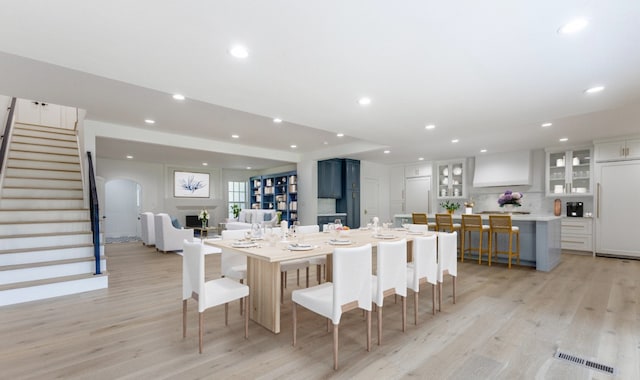 kitchen featuring light wood-type flooring, white cabinets, built in fridge, a breakfast bar area, and a large island