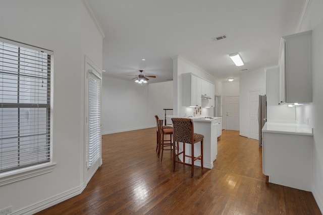 kitchen with ceiling fan, stainless steel fridge, kitchen peninsula, dark wood-type flooring, and white cabinetry