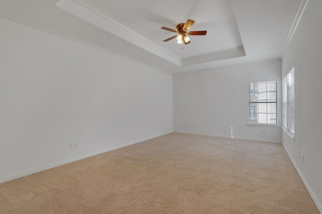 unfurnished room featuring crown molding, a tray ceiling, light carpet, and ceiling fan