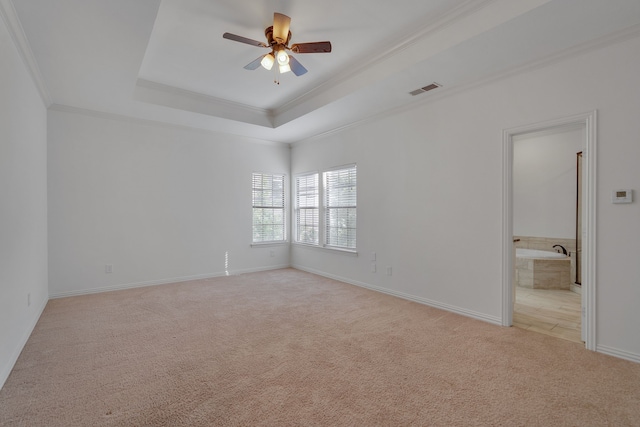 interior space with ceiling fan, light colored carpet, a tray ceiling, and ornamental molding