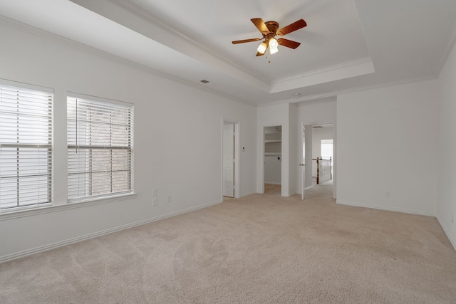 unfurnished bedroom with a raised ceiling, ceiling fan, light colored carpet, and crown molding