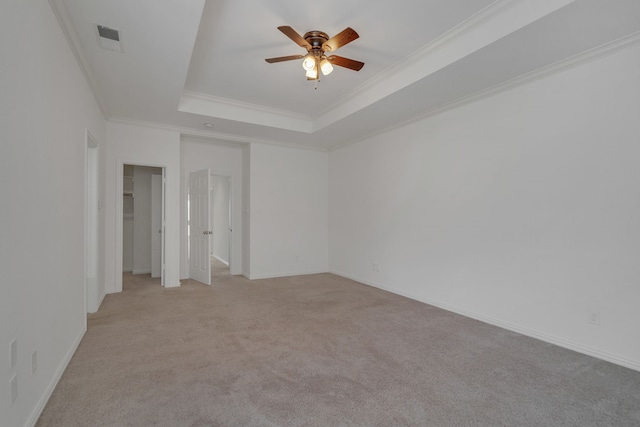 carpeted empty room featuring ceiling fan, a tray ceiling, and crown molding