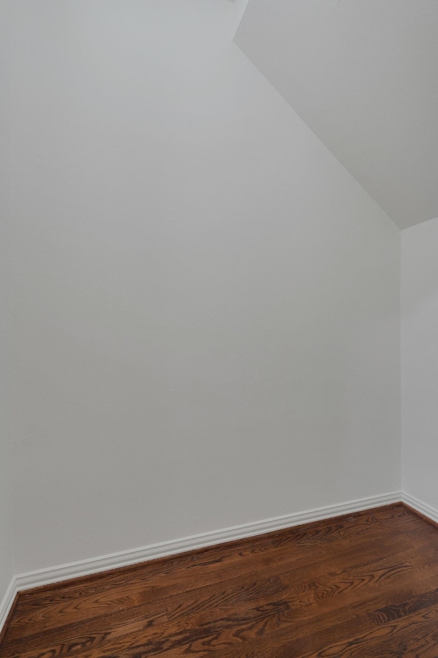 additional living space featuring vaulted ceiling and dark wood-type flooring